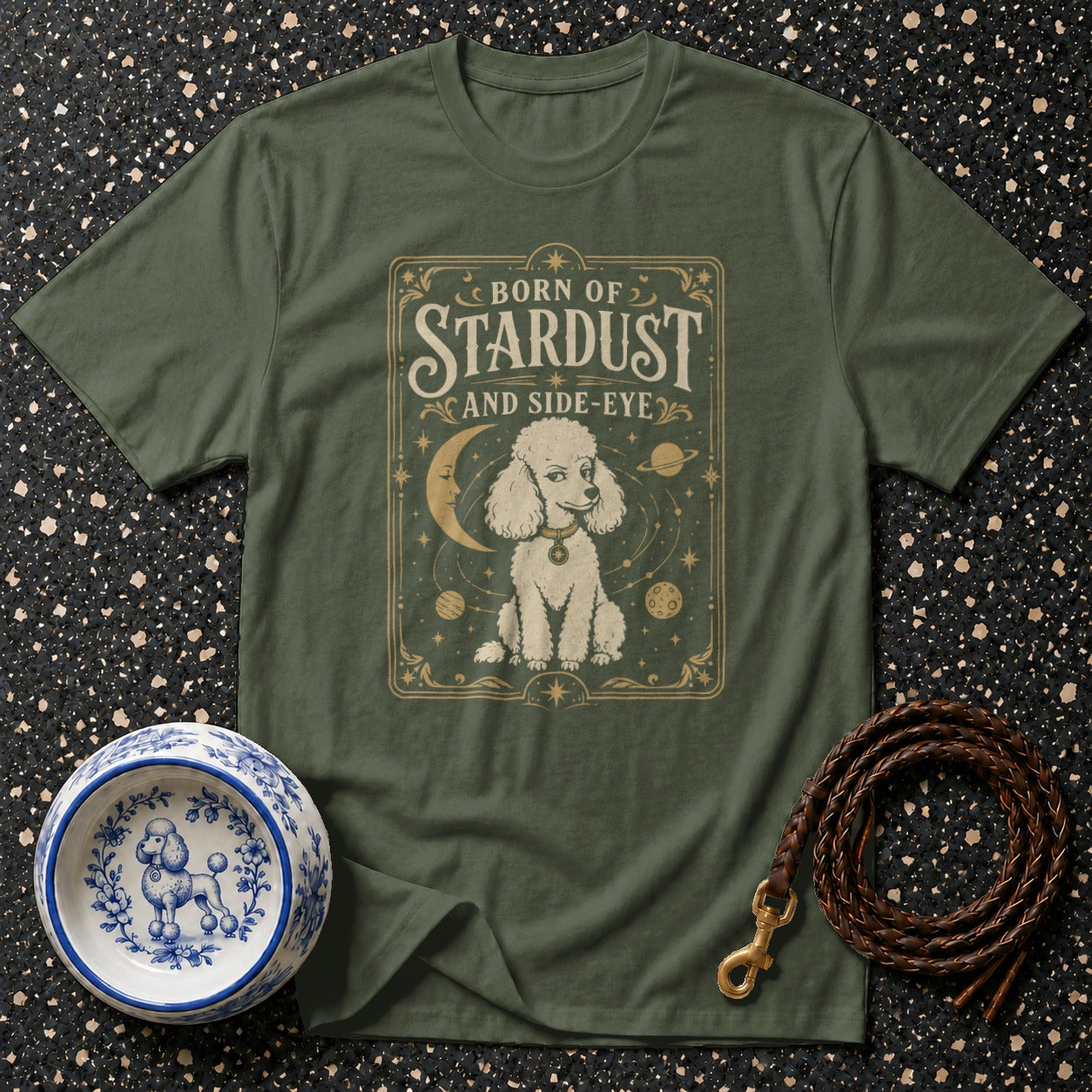 Green t-shirt with a poodle and celestial design, text "Born of Stardust and Side-Eye".