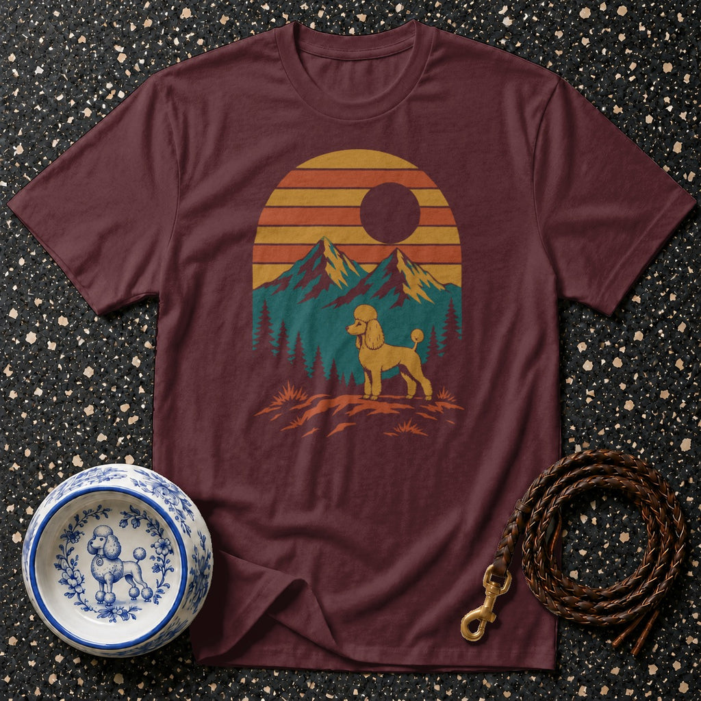 Maroon t-shirt with a yellow poodle graphic against a mountain sunset landscape.