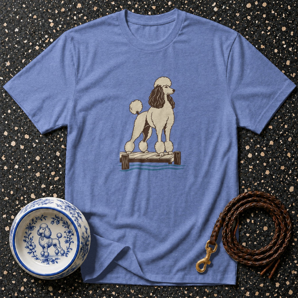 Blue t-shirt with a poodle illustration on a dock next to a decorative dog bowl.