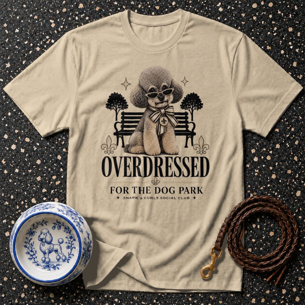 Light tan t-shirt with cartoon poodle wearing sunglasses and text "OVERDRESSED FOR THE DOG PARK."