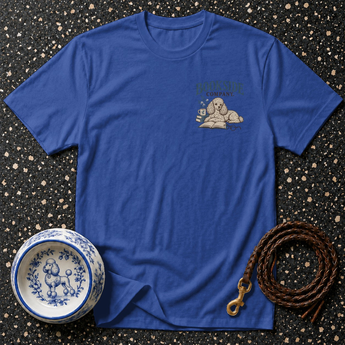 Blue t-shirt with a poodle illustration on an open book, a coffee cup, and glasses.