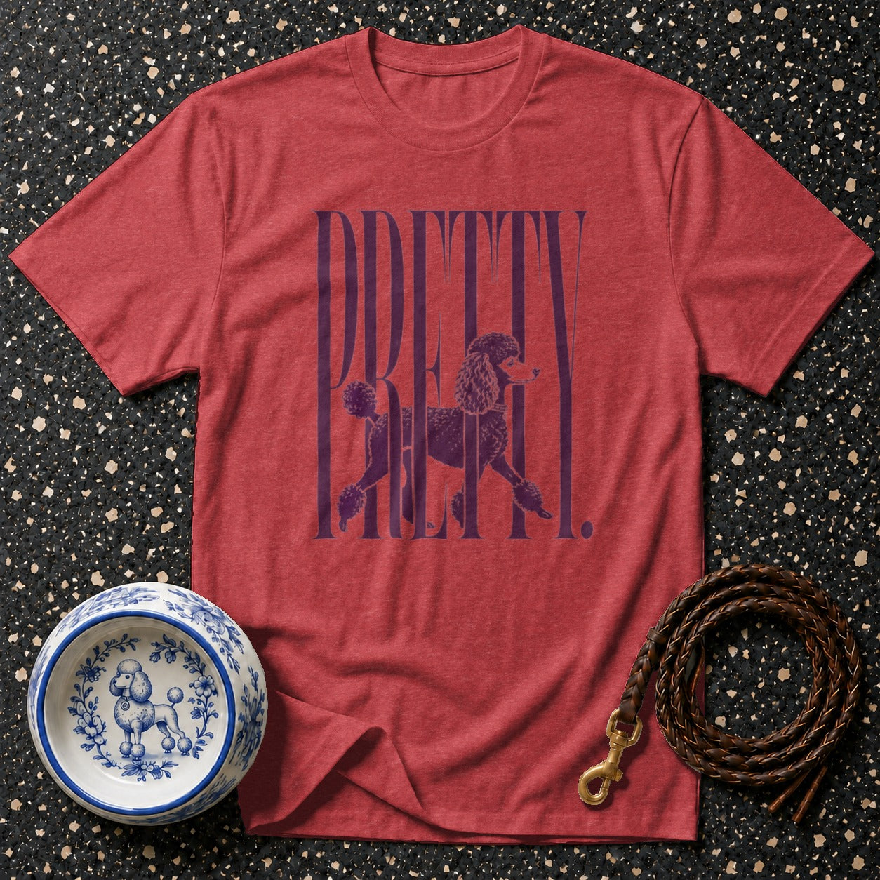 Red t-shirt with purple text "PRETTY" and poodle graphic, next to a dog bowl and leash.