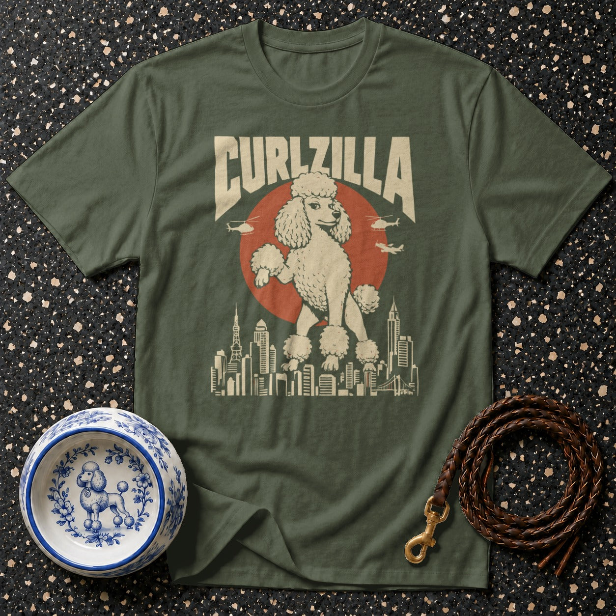 Green t-shirt with a graphic of a poodle in a city with the text CURLZILLA.