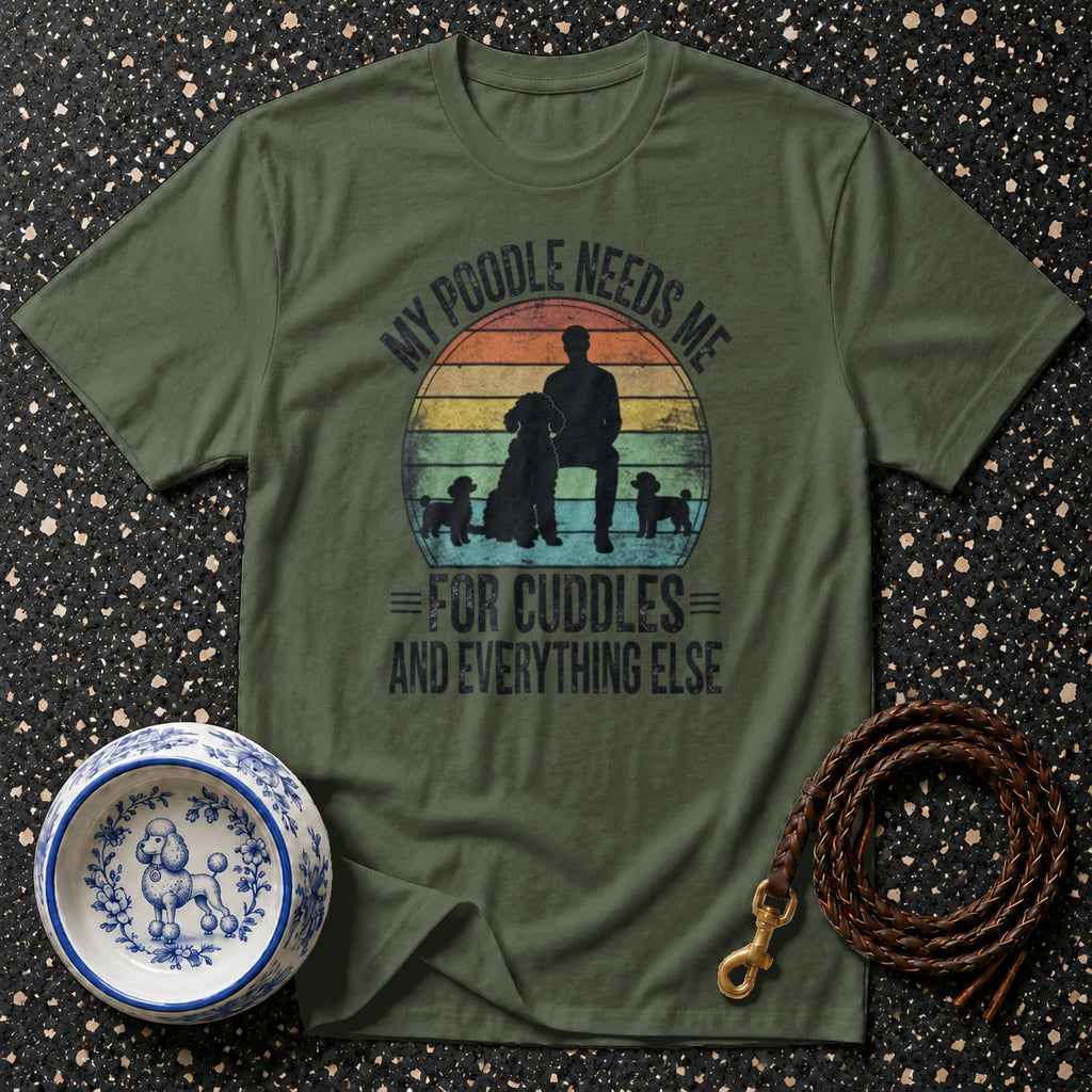Olive green t-shirt with a design featuring a person and poodles with text "My Poodle Needs Me For Cuddles And Everything Else".