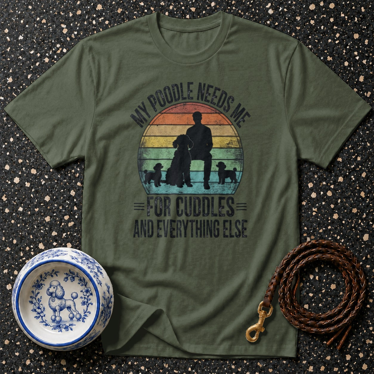Olive green t-shirt with a design featuring a person and poodles with text "My Poodle Needs Me For Cuddles And Everything Else".
