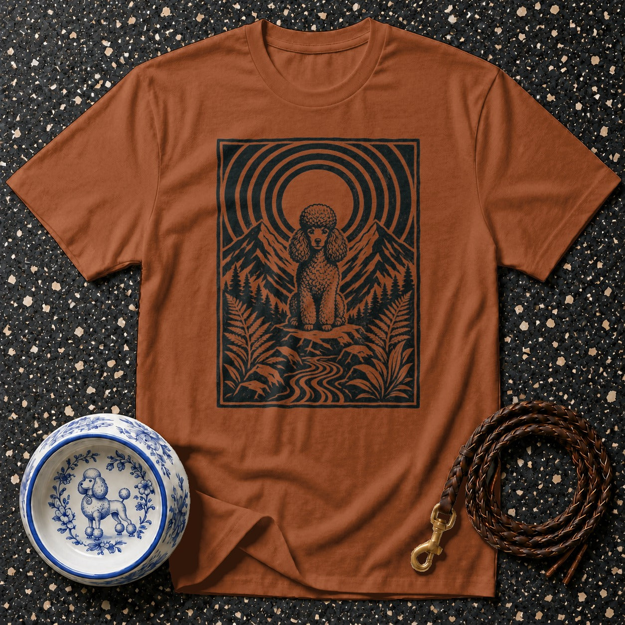 Brown t-shirt with black graphic of a poodle in mountains and a decorative dog bowl.