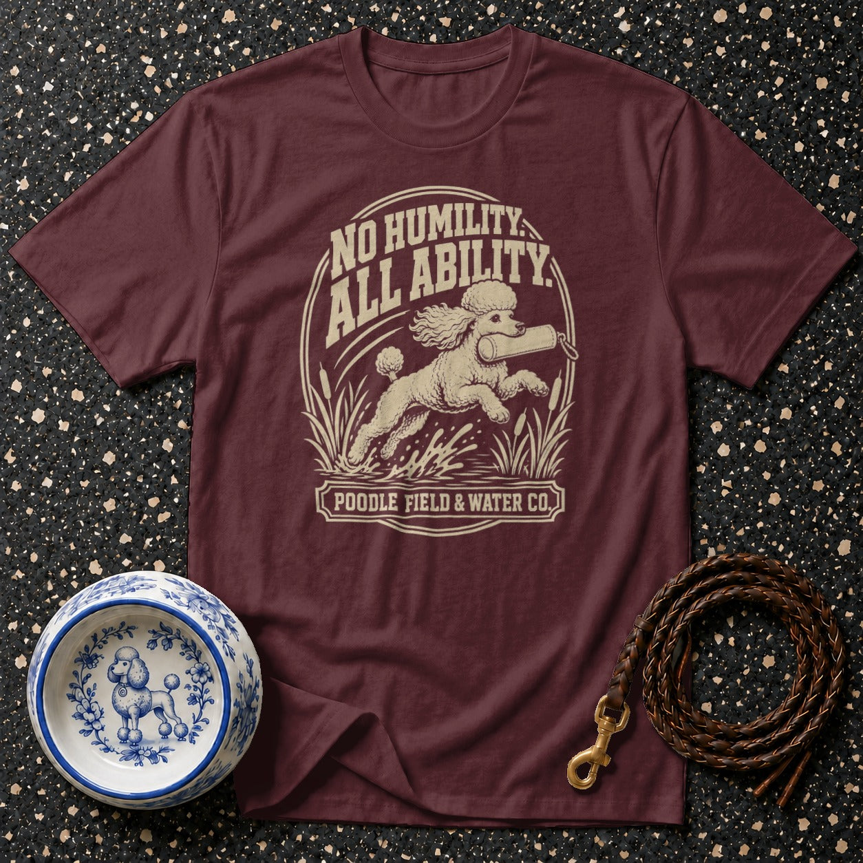 Maroon t-shirt with a poodle graphic that reads "No Humility, All Ability" and "Poodle Field & Water Co."