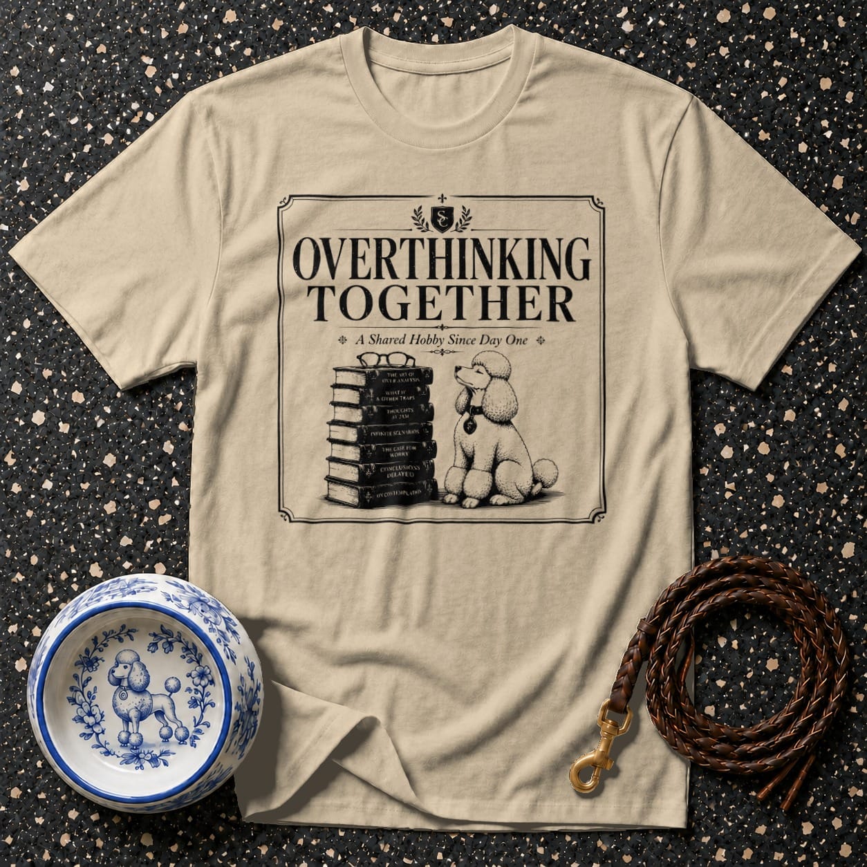 T-shirt with "Overthinking Together", stack of books, glasses, and poodle.