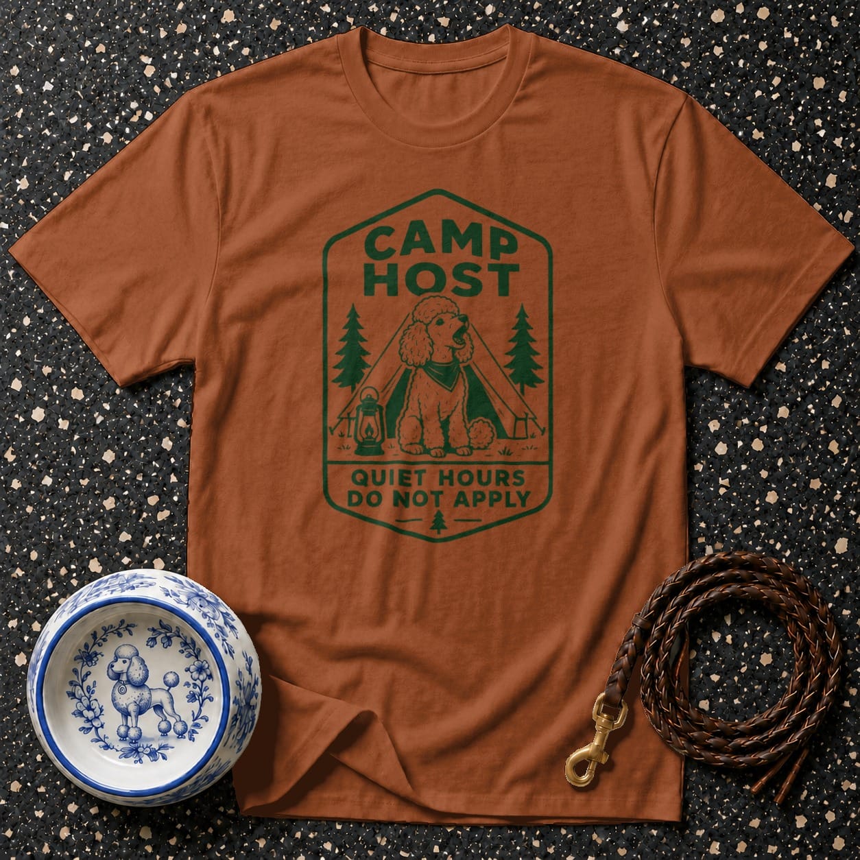 Brown t-shirt with green "Camp Host" graphic featuring a poodle, tent, lanterns, and trees.